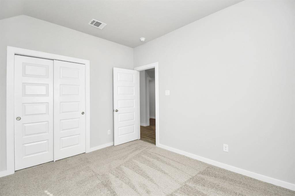 Secondary bedroom features plush carpeting, large windows that let in plenty of natural light, bright paint, and spacious closets.