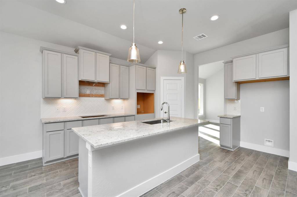 Discover another perspective of this stunning kitchen, generously appointed with an abundance of counter space. Sample photo of completed home with similar plan. As built color and selections will vary.