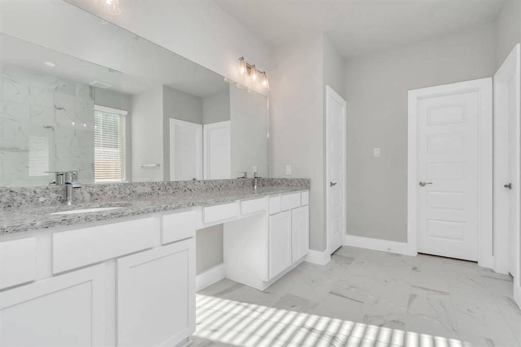 Alternative view of the expansive primary bathroom, showcasing a dedicated vanity area, sophisticated and modern finishes that redefine luxury.  Sample photo, as built color and selections may vary.