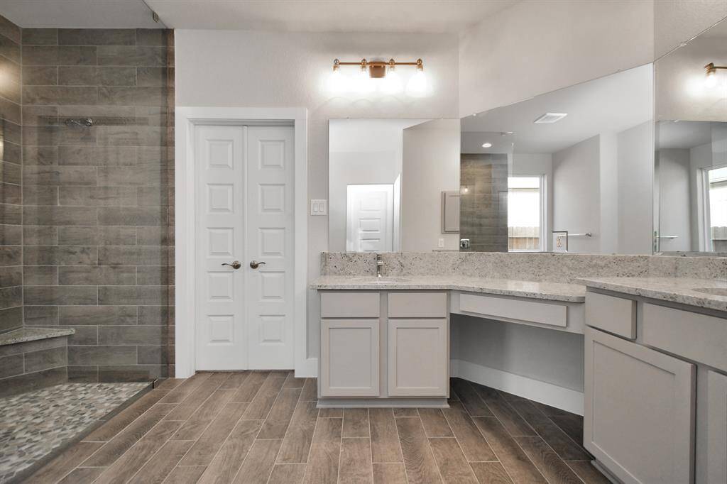Full length mirrors, double sinks, modern vanity lights, and sleek hardware make this primary bathroom a sophisticated oasis of contemporary elegance and functionality. Sample photo of completed home with similar plan. As built color and selections will vary.