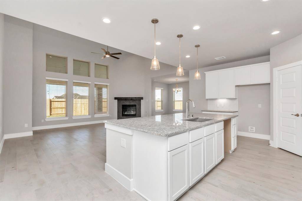 This generously spacious kitchen is a dream realized! With a massive granite island, high ceilings, soft close cabinets, granite countertops, stainless steel appliances, a sleek tile backsplash, recessed lighting, and an extended counter area, it offers both style and practicality. All this opens up to the expansive family room, creating a perfect hub for gatherings.  Sample photo, as built color and selections may vary.