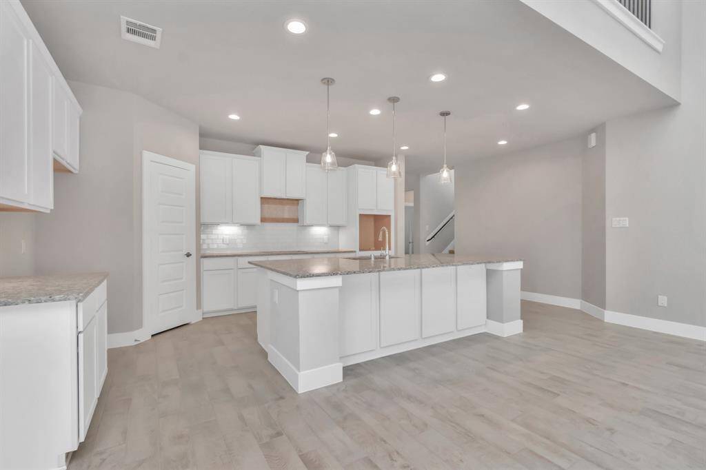 Take in another perspective of this impressive open and bright kitchen. Revel in the abundance of space designed to enhance functionality and elevate your culinary experience.  Sample photo, as built color and selections may vary.