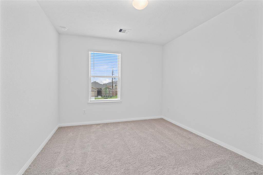 Secondary bedroom features plush carpet, custom paint, lighting, closet space, and a large window with blinds!