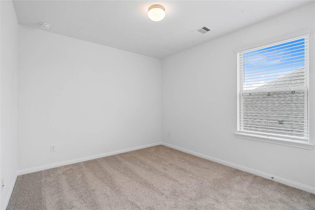 Secondary bedroom features plush carpet, custom paint, lighting, closet space, and a large window with blinds!