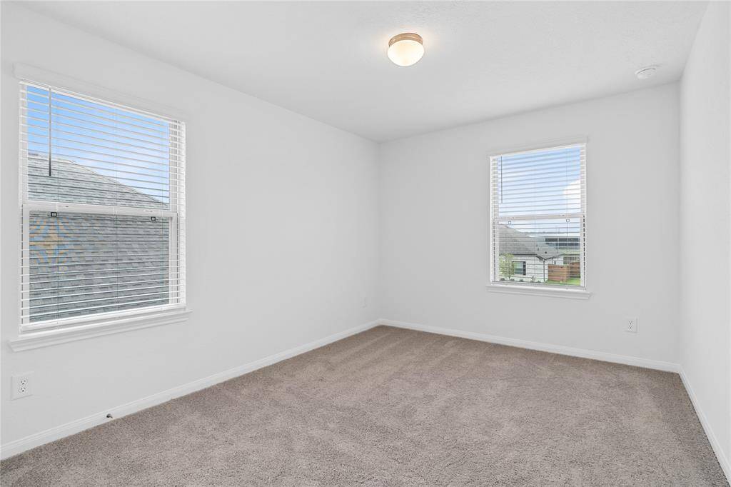 Secondary bedroom features plush carpet, custom paint, lighting, closet space, and a large window with blinds!