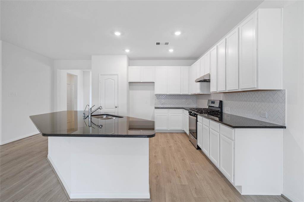 This stunning kitchen displays such a beautiful contrast with the white stained cabinets and dark granite countertops, neutral paint, kitchen island with extended breakfast bar, modern tile backsplash, SS appliances, recessed lighting, high ceilings and pantry.