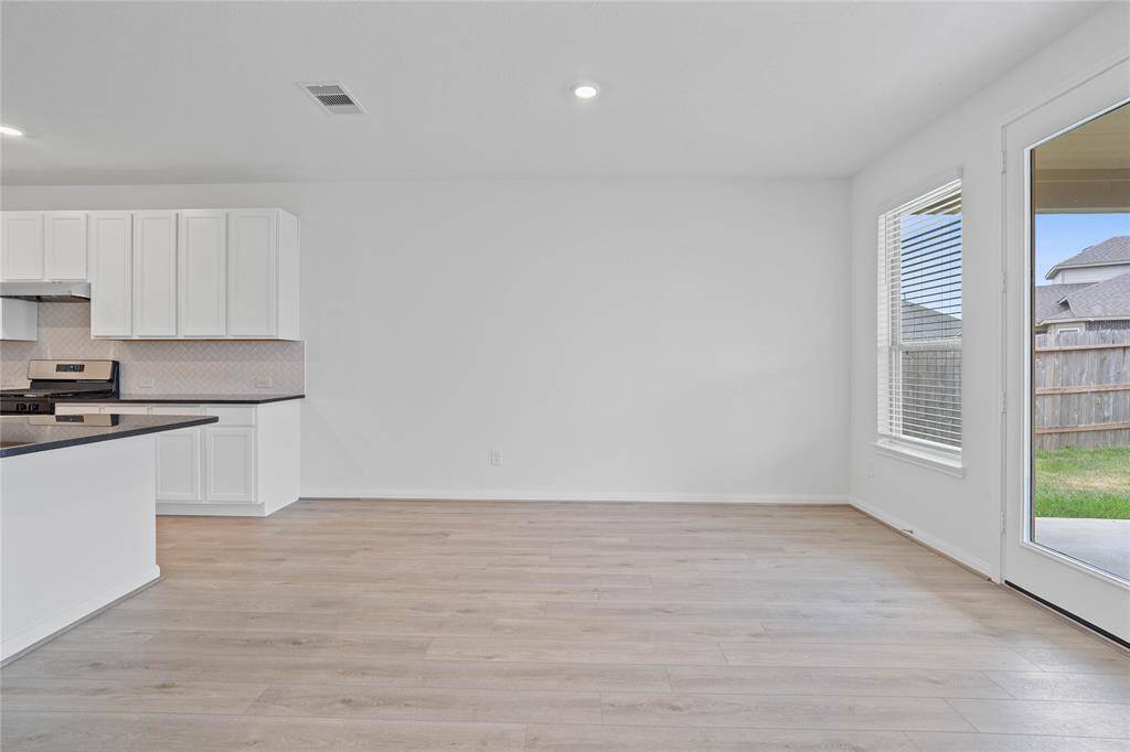 This lovely dining area is perfect for starting the day out on the right foot! This space showcases custom paint, high ceilings, recessed lighting, large window adding to the ample natural light in the kitchen, access to the back yard, and vinyl plank flooring!