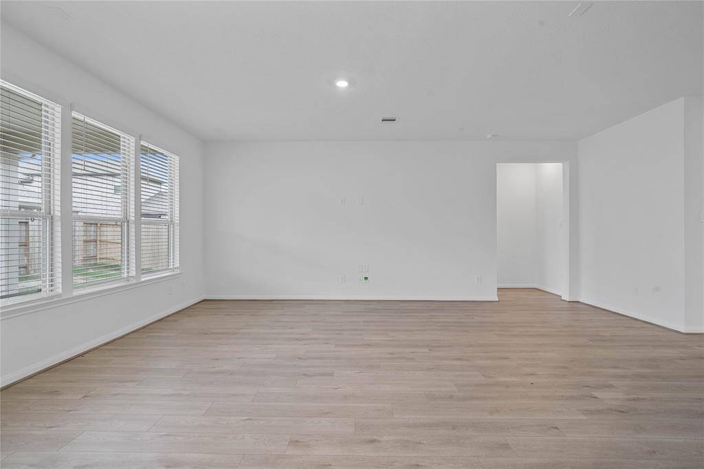 This light and bright spacious family room is the perfect layout for entertaining or just relaxing. Whether it's simply a night in or entertaining family and friends, this home has ample open space for everyone to enjoy! Featuring vinyl plank flooring, large windows, 2" faux wood blinds, recessed lighting and custom paint!