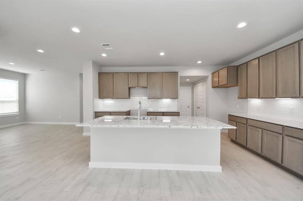 Welcome family and guests to your charming living room! With its high ceilings, recessed lighting, ceiling fan, custom paint, beautiful flooring, and large windows that let in abundant natural light, this room is perfect for gatherings.