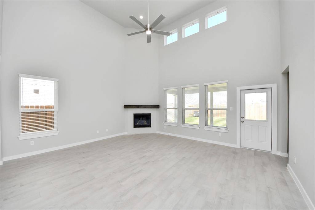 Relax and unwind in this inviting family room, illuminated by abundant natural light streaming in through tall windows, complemented by high ceilings and stunning flooring. Stay comfortable year-round with the gentle breeze from the ceiling fan, creating the perfect atmosphere for family gatherings.