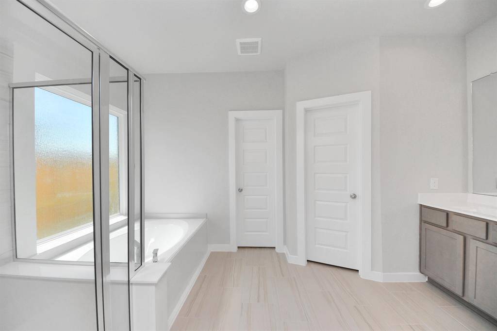Indulge in a spa-like retreat within the confines of this primary bathroom. Delight in a spacious walk-in shower enveloped in stylish tile surround and unwind in a separate garden tub adorned with custom detailing!