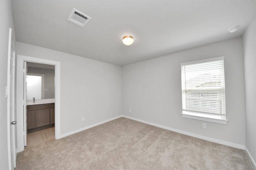 Secondary bedroom features plush carpeting, large windows that let in plenty of natural light, bright paint, and spacious closets.