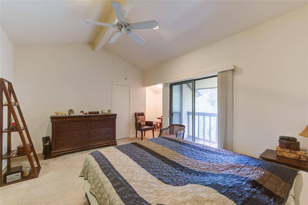 The primary bedroom offers a serene retreat with direct access to a small closet centrally located, a home office to the left, and a private balcony, overlooking wooded area, enhancing both relaxation and functionality.
