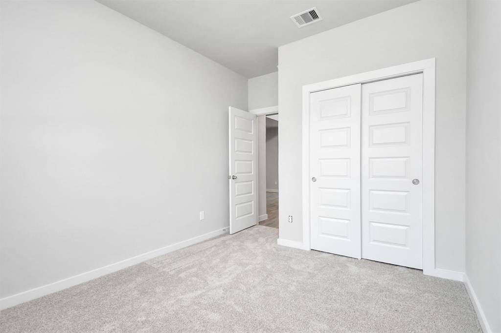 Quietly nestled in front of the home is a guest suite. Featuring plush carpet, custom paint and large window with privacy blinds. Sample photo of completed home with similar floor plan. As-built interior colors and selections may vary