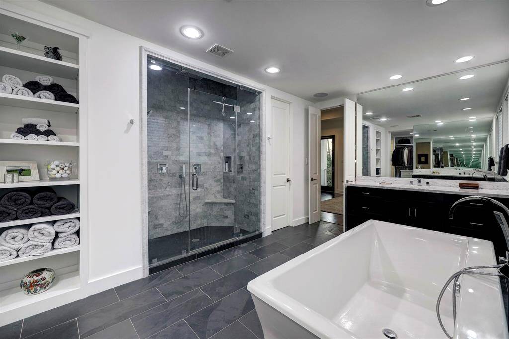 Primary bath has an oversized shower soaking tub, tile and subway tile details. His/her vanity spaces. Iridescent neutral blinds let in plenty of light.