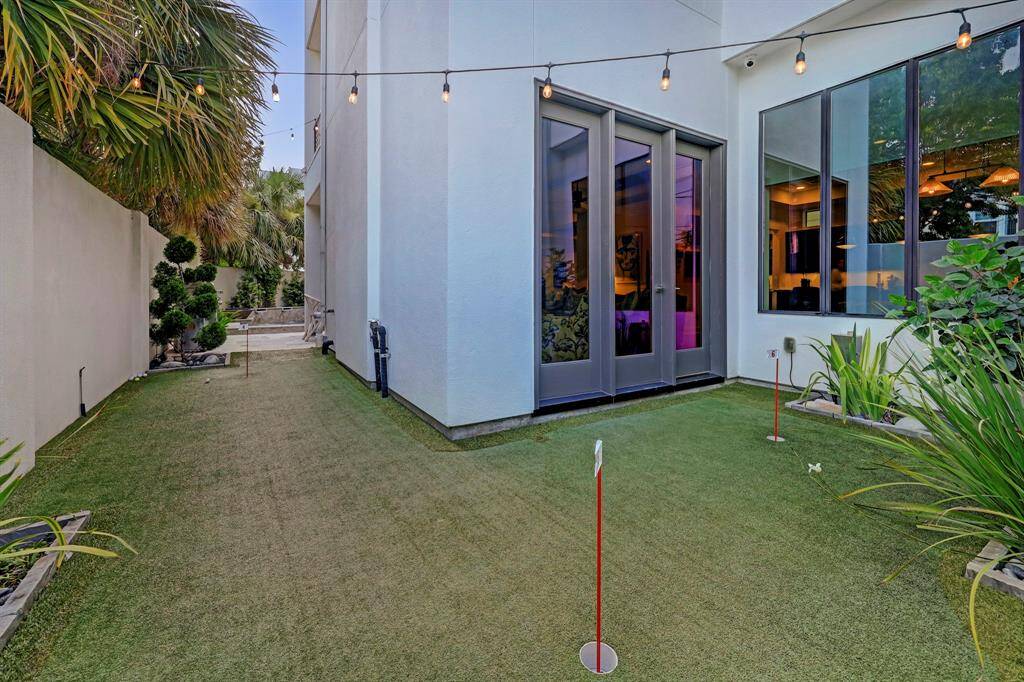 Closer view of 6 hole putting green for the golfers. Plenty of turfed green space for pets and play which wraps around the family room and breakfast rooms. One may practice in the evening-under the string lights and exterior outdoor lighting.
