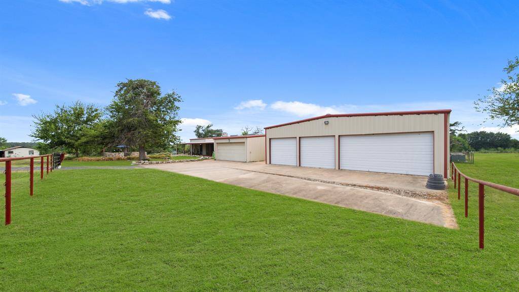 This property features a spacious, detached multi-car garage with a large driveway with painted pipe fence and gates.