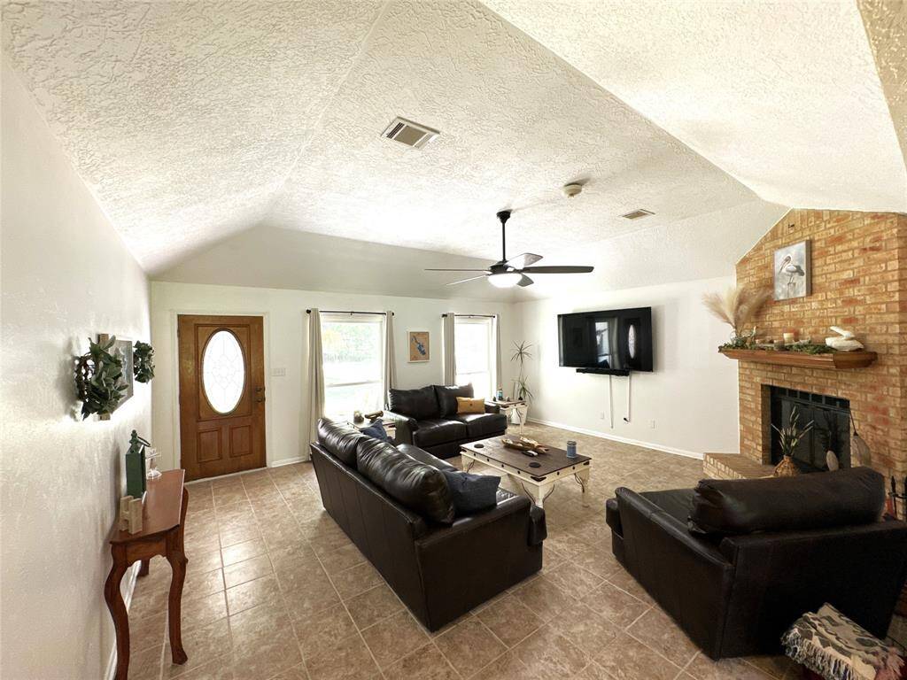 Spacious living room with cozy fireplace and abundant natural light, viewed from the dining area.
