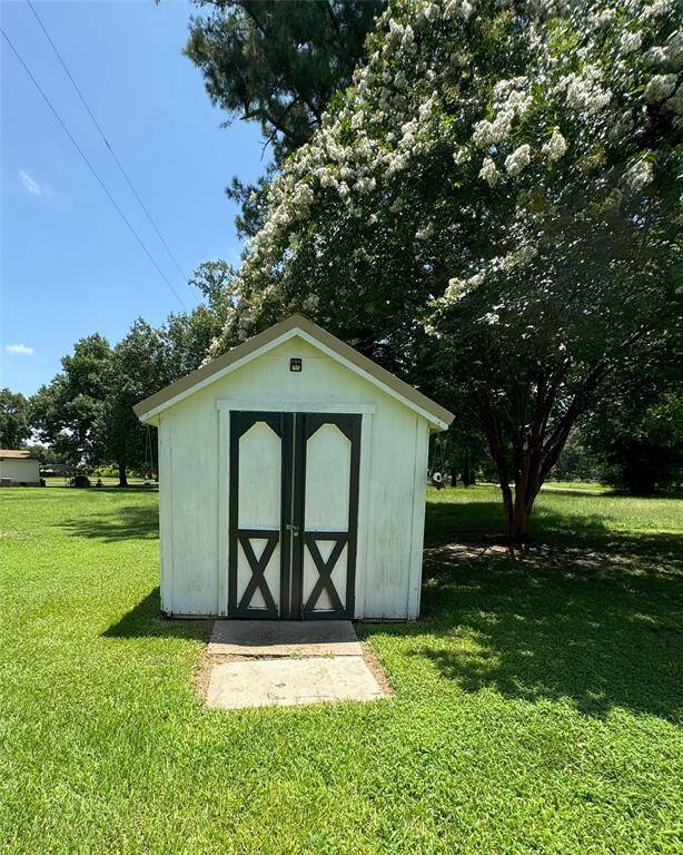 Charming outdoor shed, perfect for storage or a small workshop, nestled in a lush green setting.