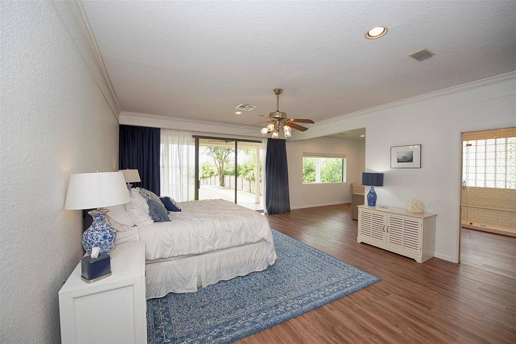 Entry to the primary bedroom located at the back of the home. Gorgeous laminate wood floors and sliding door to the patio, pool and even the lake.