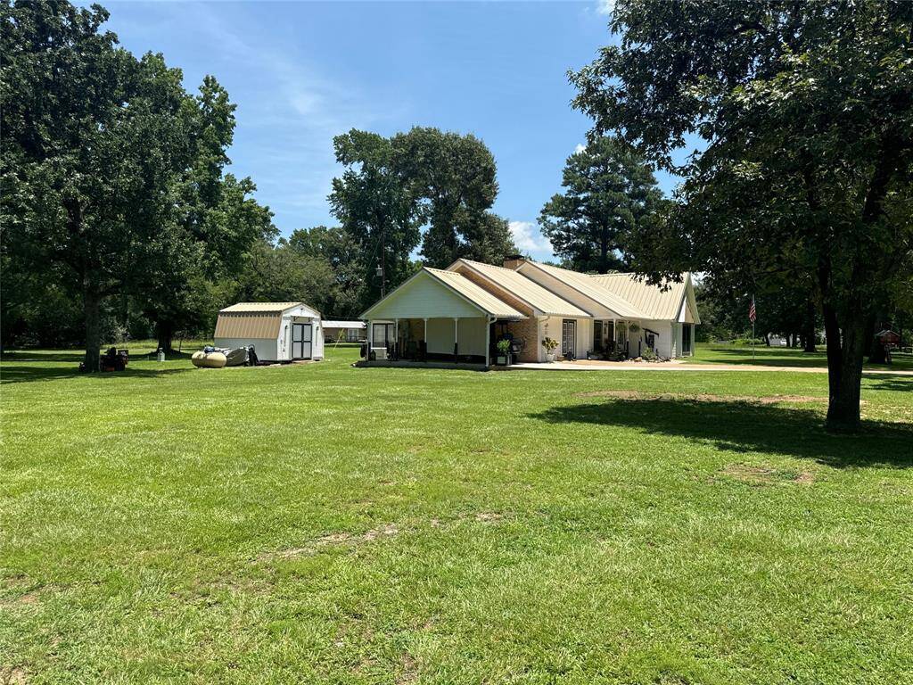 View from the left property line showcasing the workshop behind the carport and the propane tank for the new generator.