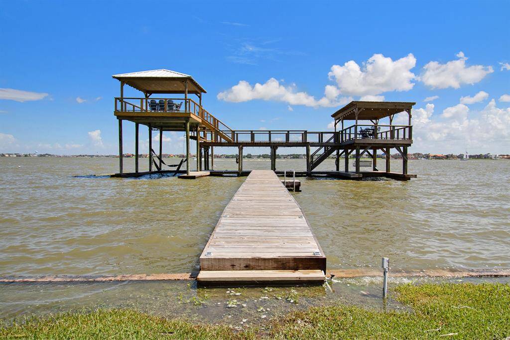 This is a waterfront property featuring a sturdy wooden pier with a covered deck area, offering a panoramic view of the water and a perfect spot for outdoor leisure or fishing.