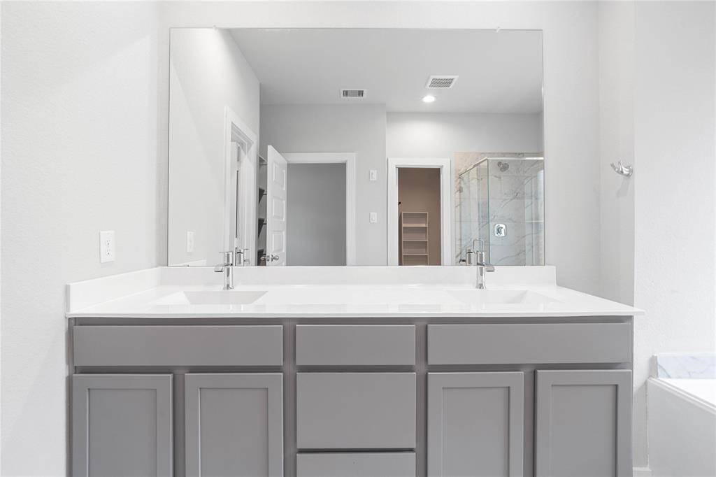 This primary bathroom is definitely move-in ready! Featuring stained cabinets with gorgeous countertops and dual sinks, spacious walk-in closet with shelving, high ceilings, custom paint, sleek and dark modern finishes.