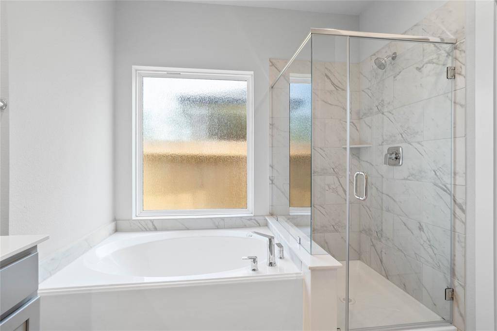 Additional view of the primary bathroom features framed walk-in shower with tile surround, separate garden tub for soaking after a long day with rain glass window, high ceilings, custom paint, sleek and dark modern finishes!