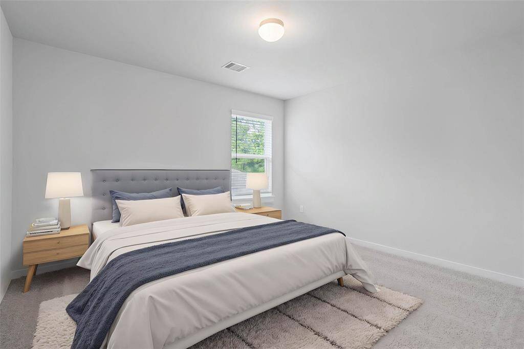 Secondary bedroom features plush carpet, custom paint, lighting, closet space, and a large window with blinds.