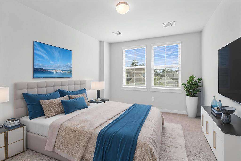 Secondary bedroom features plush carpet, custom paint, lighting, closet space, and large windows with blinds.