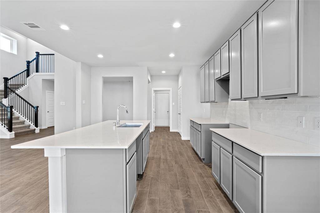 This kitchen is by far any chef’s dream! This spacious kitchen features high ceilings, stained wood cabinets, quartz countertops, modern tile backsplash, recessed lighting, quartz kitchen island with space for breakfast bar, and a walk-in pantry all overlooking your huge family room.
