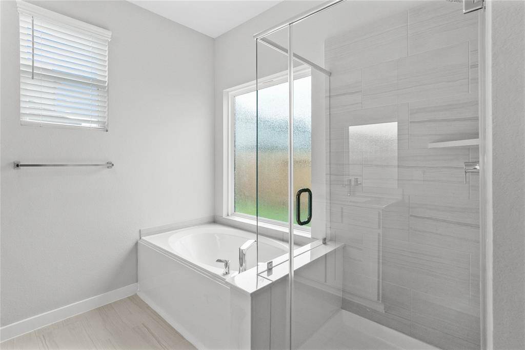 This additional view of the primary bath features a walk-in shower with tile surround and a separate garden tub perfect for soaking after a long day.