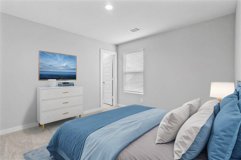 Secondary bedroom features plush carpet, custom paint, lighting, ample closet space, large window with privacy blinds, and access to a private bath.
