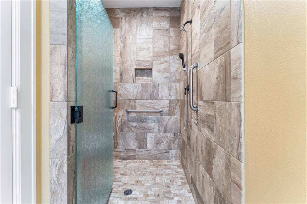 The large walk-in shower exudes a spa-like ambiance, featuring a built-in seat and a range of additional luxurious touches.
