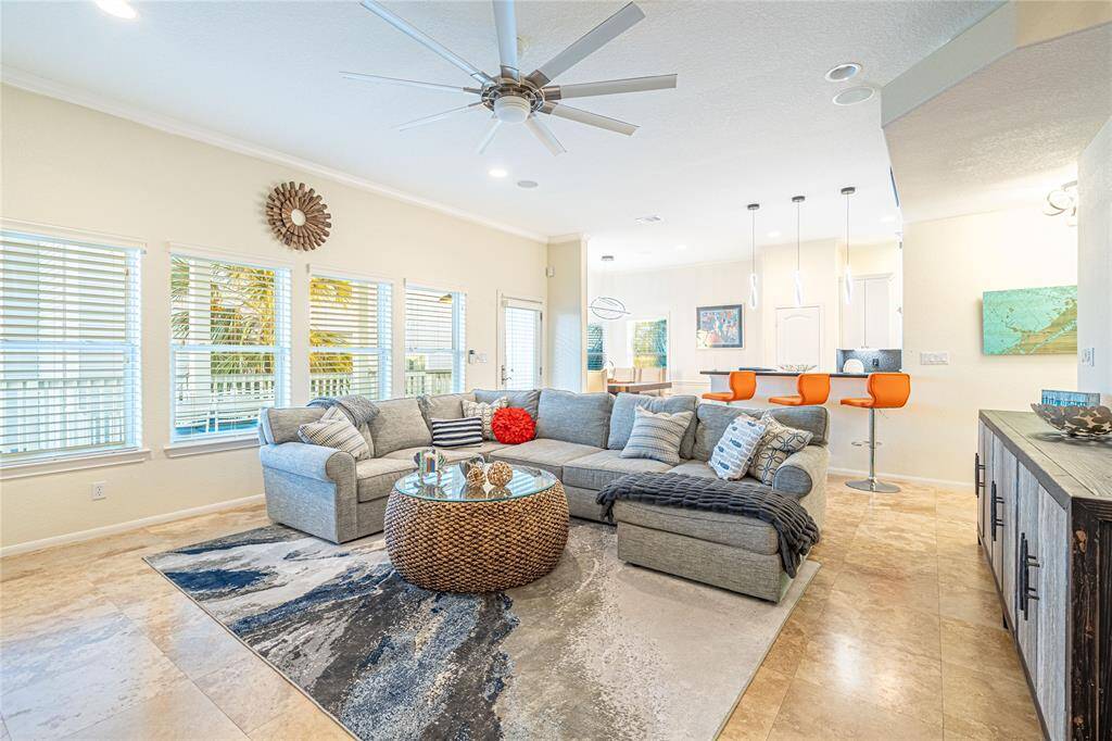Spacious and sunlit living room featuring elegant tile flooring, an open layout, and seamless flow into the kitchen and dining areas.