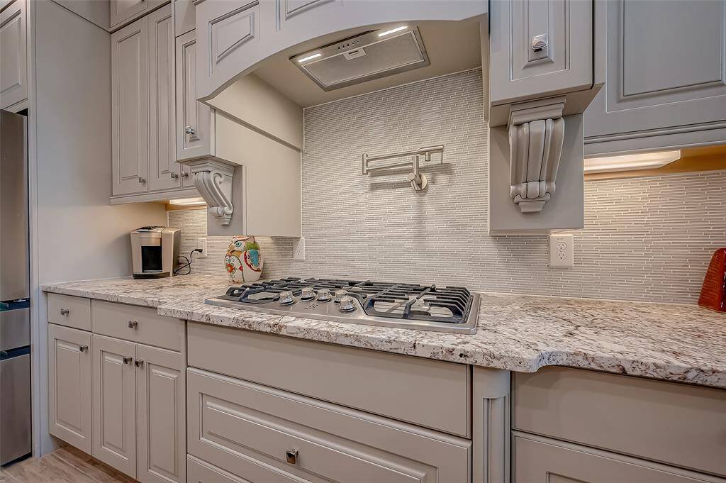 Gourmet style wood vent hood cabinet and pot filler. Built in spice racks at cooktop area, extra large drawers for pot storage. 36" 5 burner gas grate cooktop.