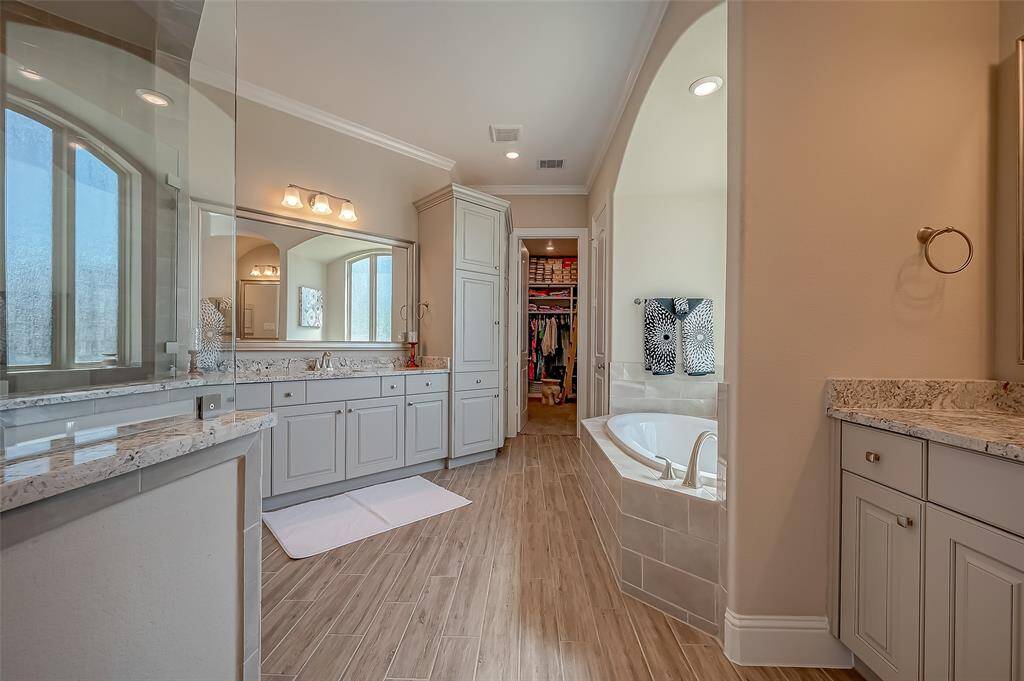 Step into a primary bath designed for ultimate relaxation and sophistication. This stunning space features exquisite 18-inch floor-to-ceiling designer tiles that extend across both the floor and shower walls, creating a seamless and luxurious backdrop of rich texture and visual interest.