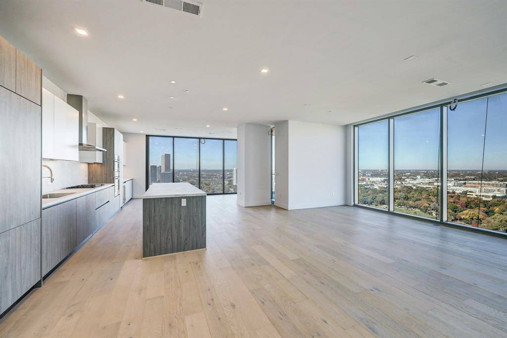 This is a modern, open-concept living space featuring a spacious kitchen with sleek Pedini cabinetry and a central island, porcelain counter tops and back splash.The home is complemented by light hardwood flooring throughout and ample natural light from large windows.