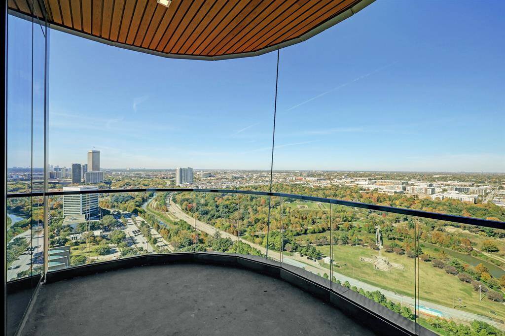 The spacious balcony features panoramic view of the city skyline and lush green park areas.