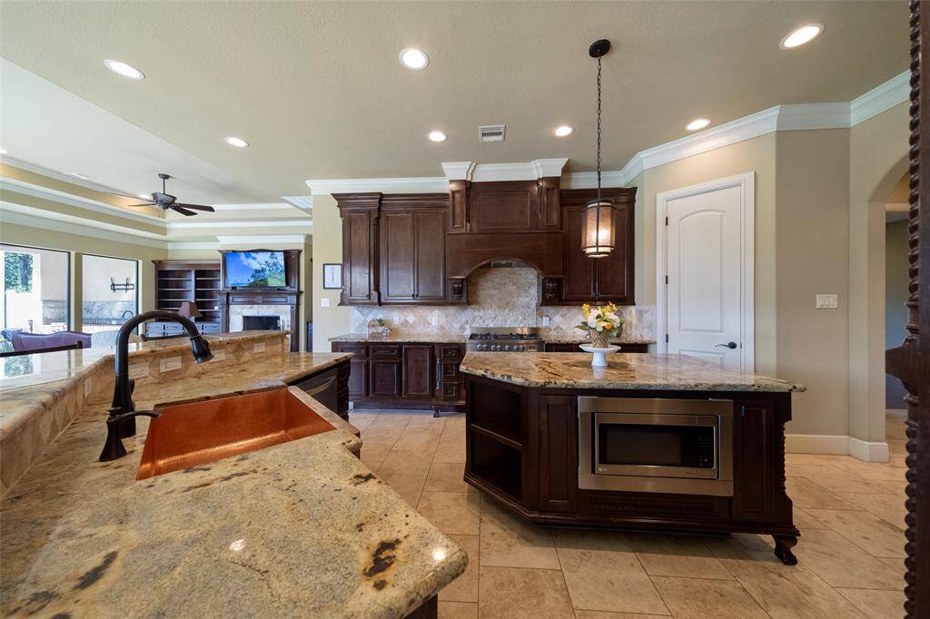Discover a radiant chef's kitchen outfitted with sleek stainless steel appliances, an elegant copper sink, and convenient pull-out storage drawers.