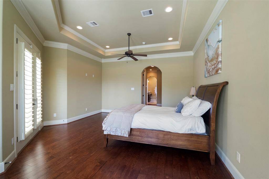 Spacious bedroom with ample space for furnishings, complemented by an elegant archway leading to an en-suite spa-inspired master bathroom.