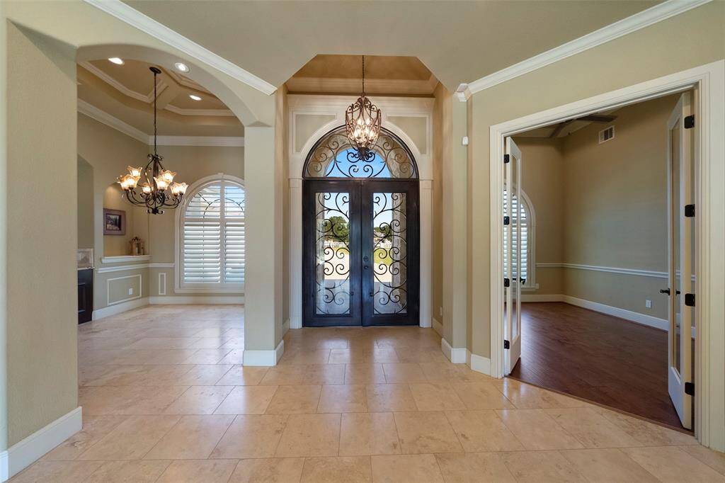 Welcome to elegance with this grand, open-concept entryway featuring high ceilings and a stunning iron door.