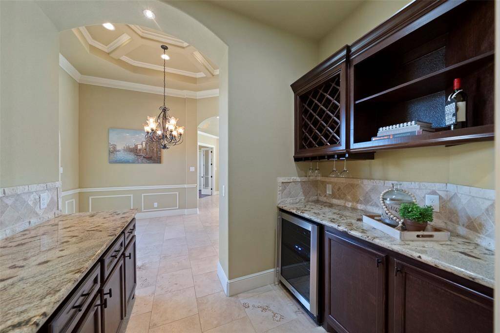 Step into sophistication with this charming butler's pantry, boasting sleek granite countertops and custom cabinetry that promise ample storage and a touch of luxury for seamless entertaining.