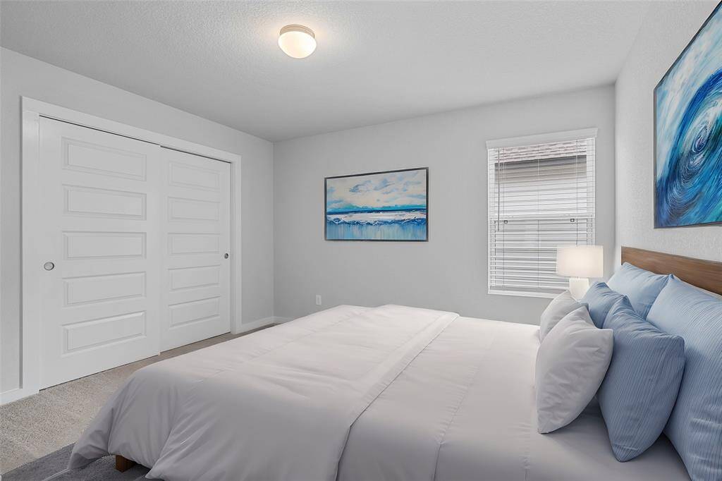 This secondary bedroom features high ceilings, recessed lighting, custom paint, plush carpet, ample closet space, and a large window with privacy blinds!