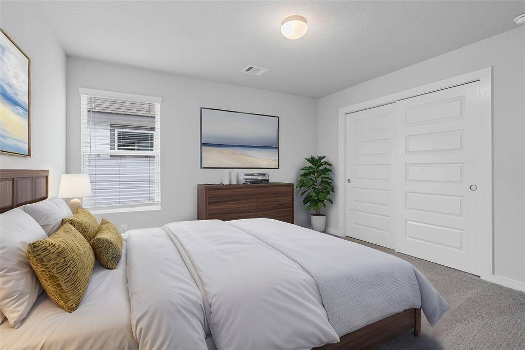 This secondary bedroom features high ceilings, recessed lighting, custom paint, plush carpet, ample closet space, and a large window with privacy blinds!