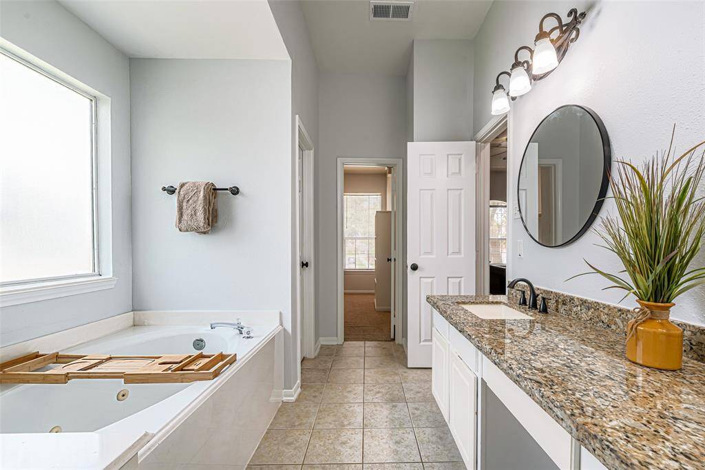 The primary offers granite countertops, large soaking tub and a frameless shower.