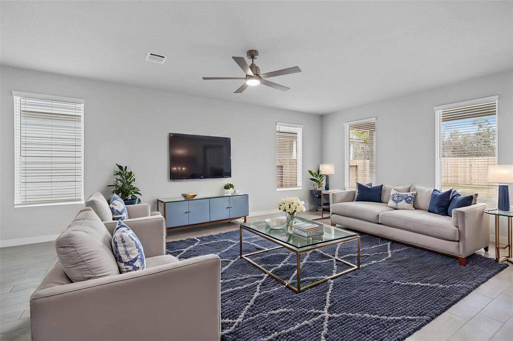 This family room is a perfect room! Featuring custom paint, high ceilings with ceiling fan, wood look tile flooring, and windows with privacy blinds providing natural light into this beautiful room.