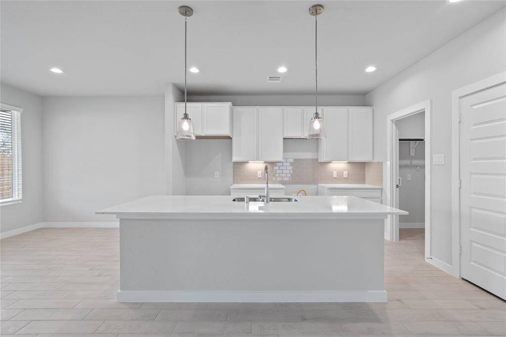 Any chef's dream, this stunning kitchen is perfect for everyday life as well as entertaining family and friends! This kitchen features stained cabinets, quartz countertops, kitchen island with extended countertop for breakfast bar, high ceilings with recessed and pendant lighting, and a pantry!