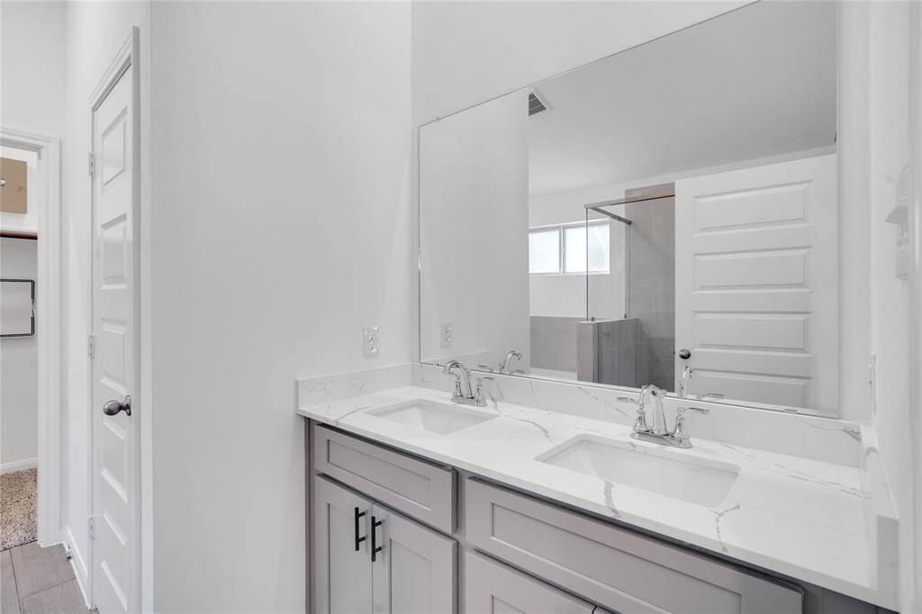 This primary bathroom is definitely move-in ready! Featuring a walk-in shower with tile surround, separate garden tub for soaking after a long day with custom tile detailing, stained cabinets with countertops, high ceilings, neutral paint, sleek and modern finishes.