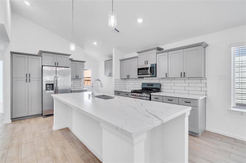 This kitchen will not disappoint! Your family and guests will enjoy many nights of fun, food and entertainment with ample counter space and kitchen island for setting up a wonderful array of provisions. This view of this gorgeous kitchen showcases SS appliances, silestone countertops, beautiful tile backsplash, gas range, double oven, high ceiling, recessed and pendant lighting and tile floors!